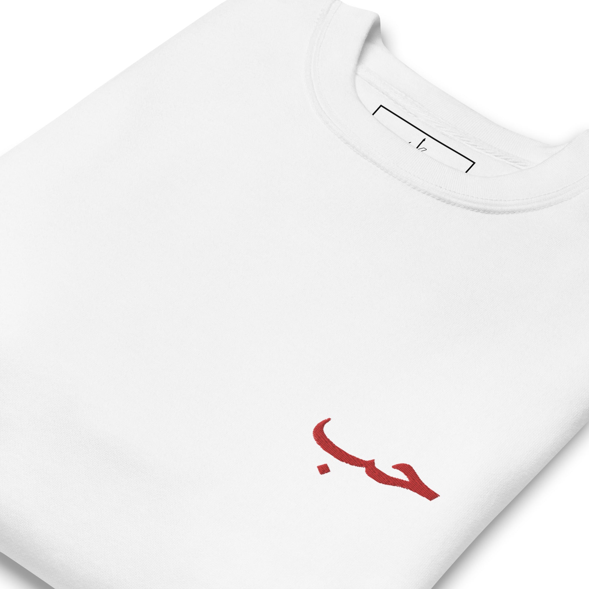 Vu de la broderie rouge du mot arabe houb écrit du pull blanc kalam clothing